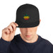 man wearing "Rasta Striped Leaf" Snapback Hat with embroidered cannabis leaf in green, yellow, and red, on a structured, adjustable cap.