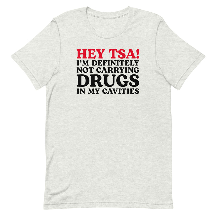 Ash color “Hey TSA! I’m Definitely Not Carrying Drugs in My Cavities” prank T-shirt with bold red and black text.