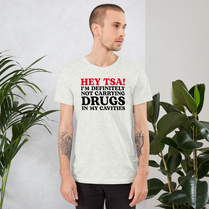 Male model wearing an Ash color “Hey TSA! I’m Definitely Not Carrying Drugs in My Cavities” prank T-shirt with bold red and black text.
