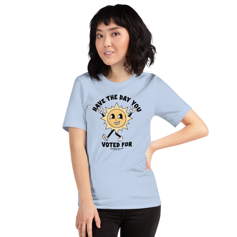 A female model wearing the baby blue "Have The Day You Voted For" t-shirt, displaying the sarcastic political design.