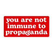 A high-contrast red sticker with the phrase "You Are Not Immune to Propaganda."
