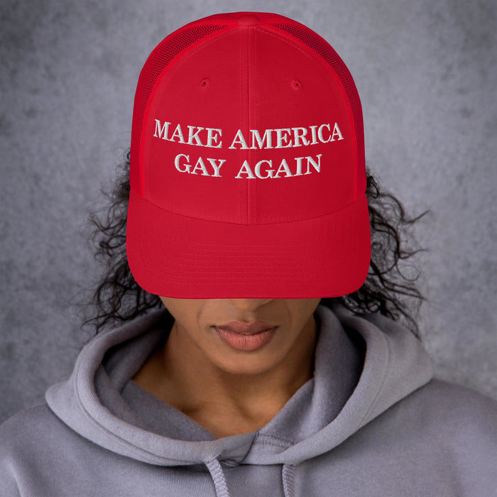 Model wearing red “Make America Gay Again” hat with curved bill, embroidered text visible above face.