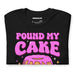 Close-up of black t-shirt showing detailed “Pound My Cake Daddy” design with pink frosting cake and sparkle accents.