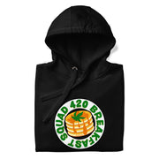 Folded black  hoodie featuring "420 Breakfast Squad" text around a design of pancakes topped with a cannabis leaf.