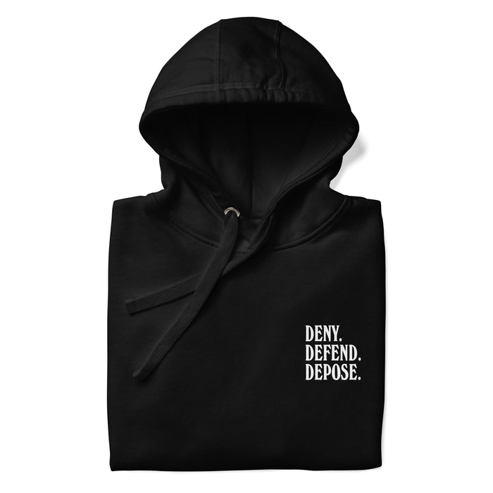 Folded up front view of the 'Deny Defend Depose' hoodie in black, featuring minimalist left chest text in bold white print.