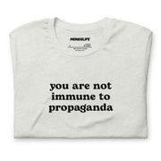 Neatly folded ash grey t-shirt showcasing the clean, simple text design reading "You are not immune to propaganda"