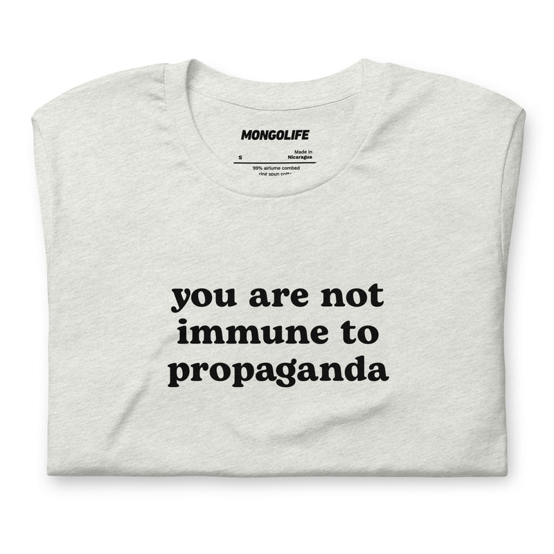 Neatly folded ash grey t-shirt showcasing the clean, simple text design reading "You are not immune to propaganda"