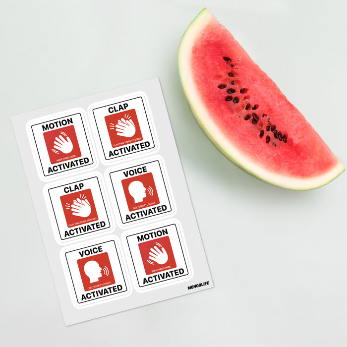 Sticker sheet of six prank “Motion/Clap/Voice Activated” labels placed on a white surface next to a slice of watermelon.