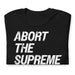 Folded Black Rebel T-Shirt featuring the text "Abort The Supreme Court" in bold distressed letters.