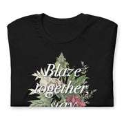 Folded Black t-shirt with "Blaze together, stay together" design featuring floral and cannabis elements.