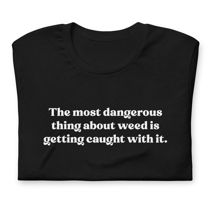 Folded Black T-Shirt with the quote "The Most Dangerous Thing About Weed is Getting Caught With It" by Bill Murray