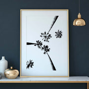 Artistic black and white silhouette of upward-view palm trees against a white background. Gold frame and interior with a blue green wall.